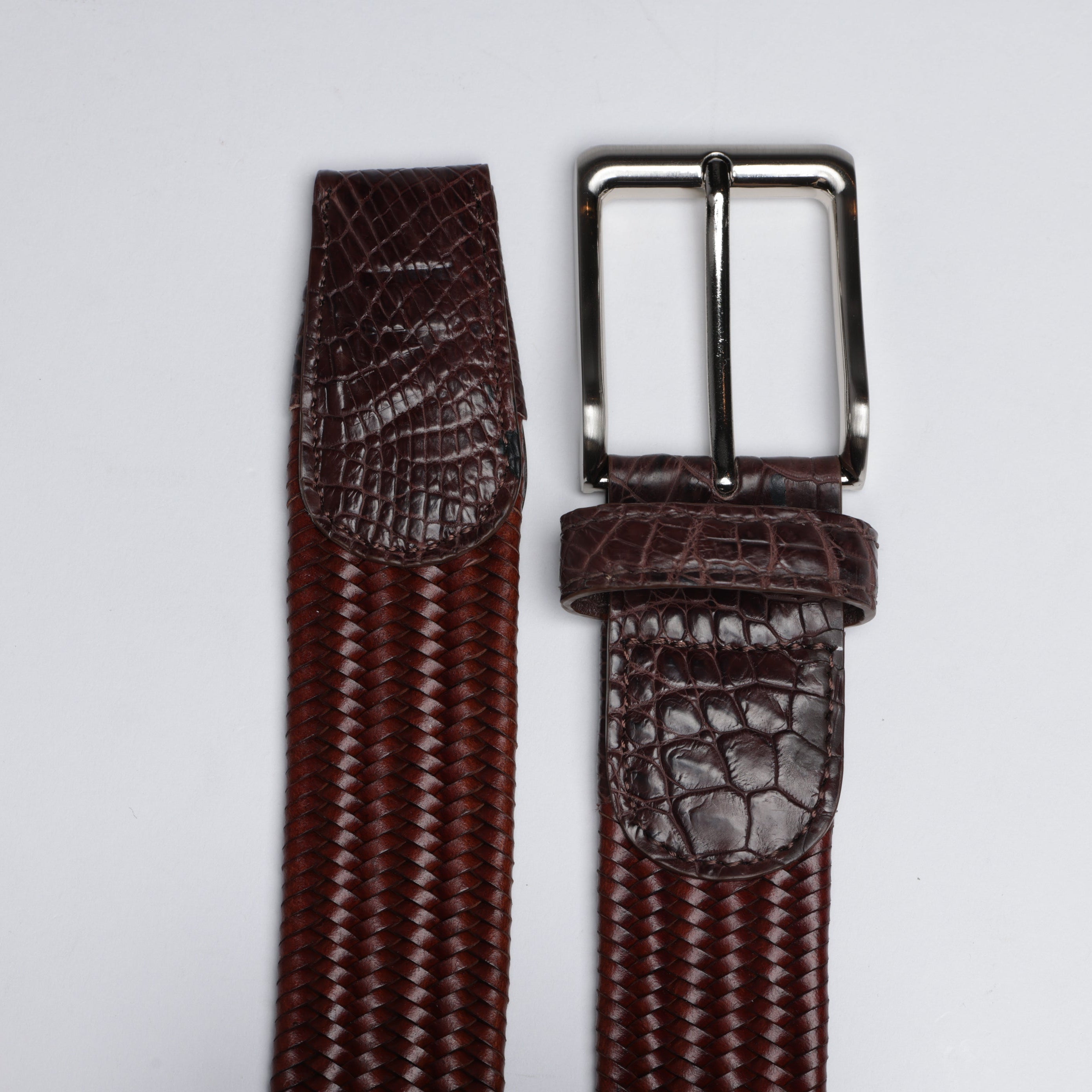 Brown textured belt with silver buckle on a light gray background